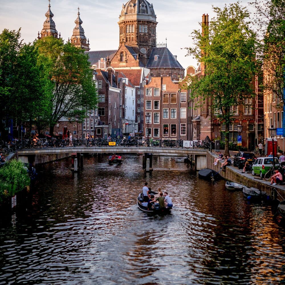 A boat passing under a canal bridge in Amsterdam at golden hour