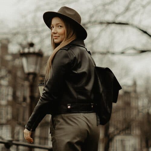Someone in a wide-brimmed hat glancing back on a canal bridge in winter