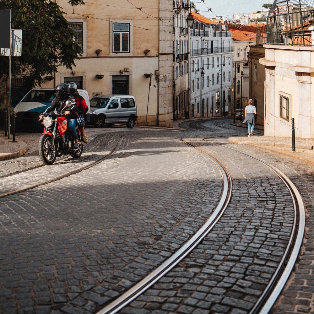 Tram tracks curving over cobbles past an ochre Lisbon facade